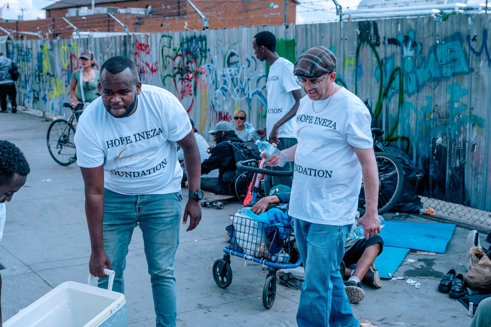 A Hope Ineza Foundation volunteer helping someone with a cart during a street outreach in Edmonton