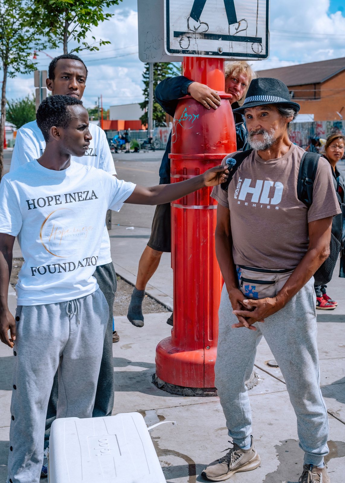 A volunteer greeting a man beside a fire hydrant during a street outreach