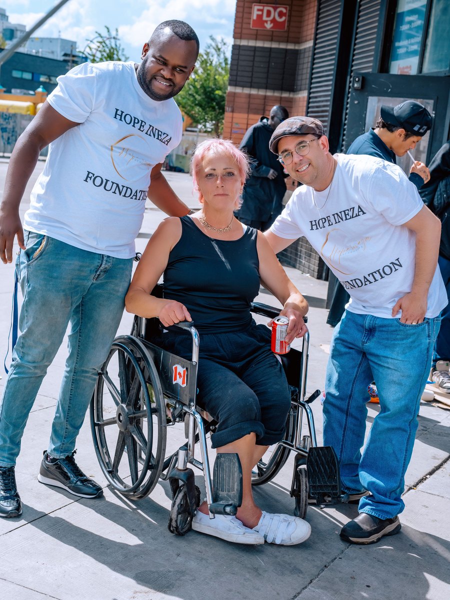 Two Hope Ineza Foundation volunteers standing either side of a woman in a wheelchair during a street outreach