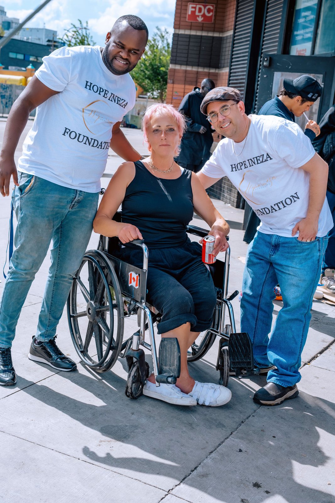 Two volunteers standing either side of a woman in a wheelchair during a street outreach