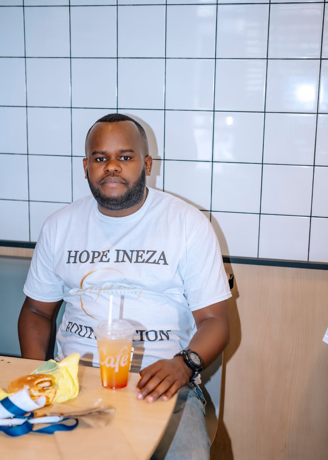 A Hope Ineza Foundation volunteer in a branded shirt seated at a table